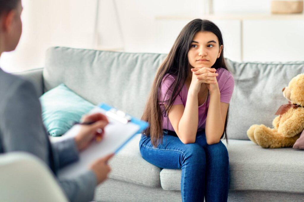 A teenager talking with a psychologist on a couch